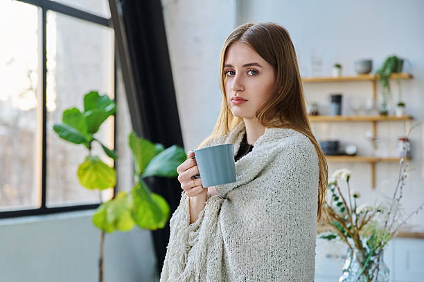 Young beautiful serious calm woman with blanket mug, looking at camera
