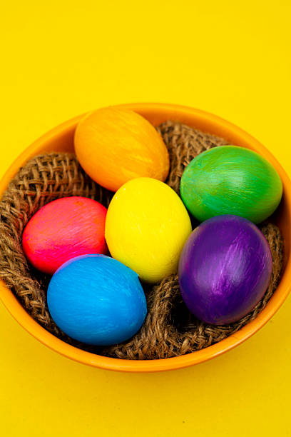 istock Colorful Easter Eggs in Orange Bowl on Yellow Background 2209785367