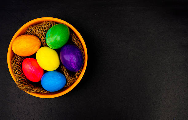 istock Colorful Easter Egg In Orange Bowl Displayed Over Black Background 2209785385