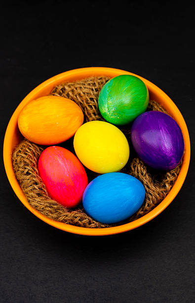 istock Colorful Eggs in Orange Bowl Over Black Background 2209785415