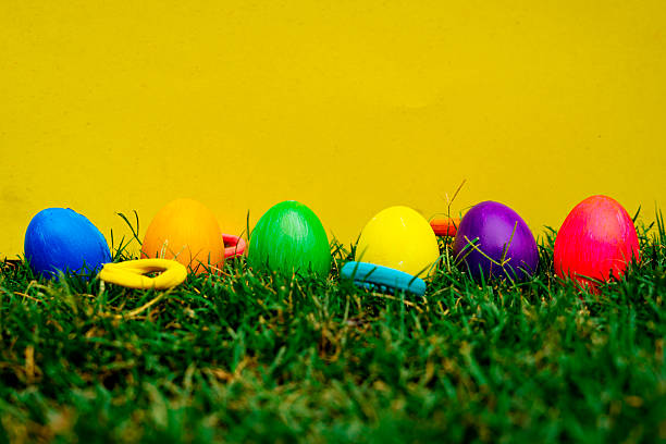 istock Easter Eggs in Green Grass against Vibrant Yellow Backdrop 2209785482