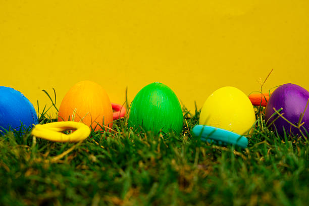 istock Colorful Easter Eggs Hidden in Grass with Yellow Background 2209785492