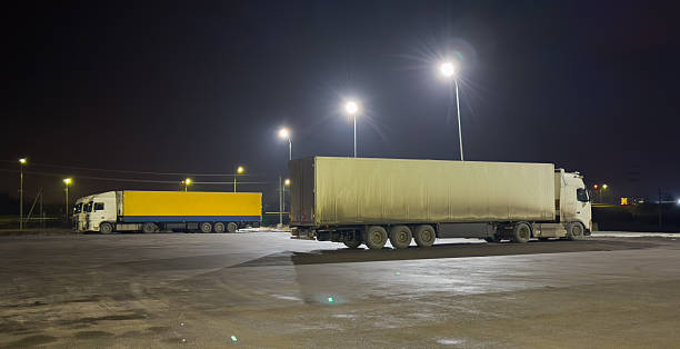 istock Two semi trucks are parked in a parking lot at night 2209785731
