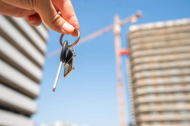 istock A person holds keys in front of a building that is currently under construction 2209786069