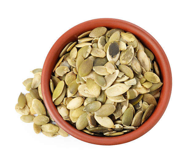 istock Peeled pumpkin seeds in bowl isolated on white, top view 2209791695