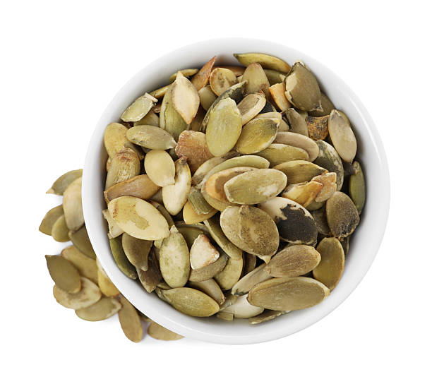 istock Peeled pumpkin seeds in bowl isolated on white, top view 2209792338