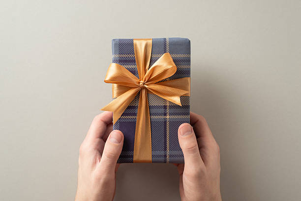 istock A wrapped gift with a golden bow being held, symbolizing celebration and giving 2209795495