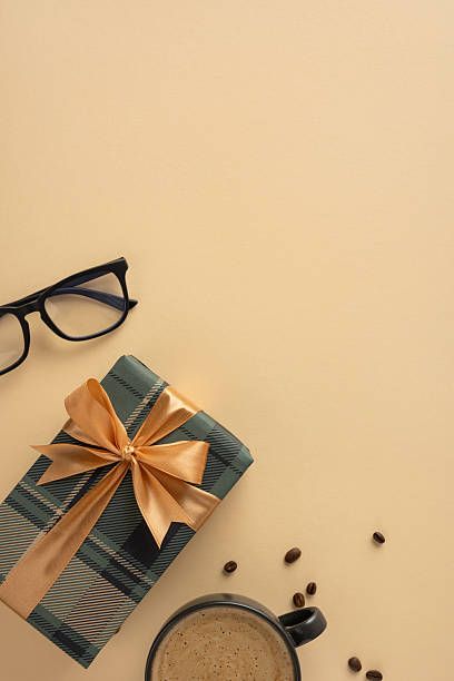 istock Beige vertical surface scene with glasses, a wrapped gift box, coffee mug, and scattered beans 2209795498