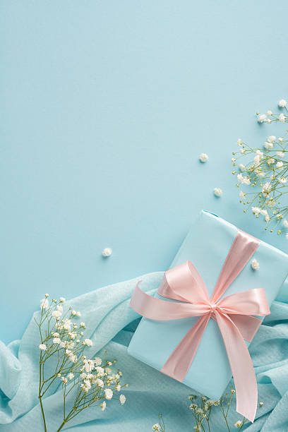 istock Stylish vertical gift wrapped with a pink ribbon, surrounded by soft fabrics and delicate flowers 2209795515