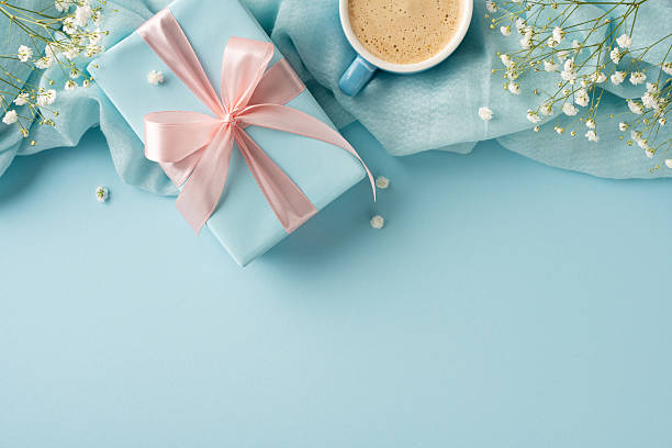 istock Pastel gift box, delicate flowers, and coffee cup arranged on a soothing blue background 2209795517