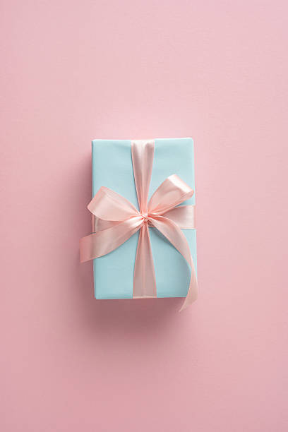 istock Gift box decorated with a silk ribbon, resting on a soft vertical pink background 2209795522