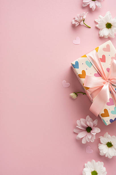 istock Gift box with heart pattern, pink ribbon, daisies, and hearts on a vertical pink background 2209795540