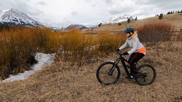istock Mature woman e-bikes along pathway in mountains 2209798470