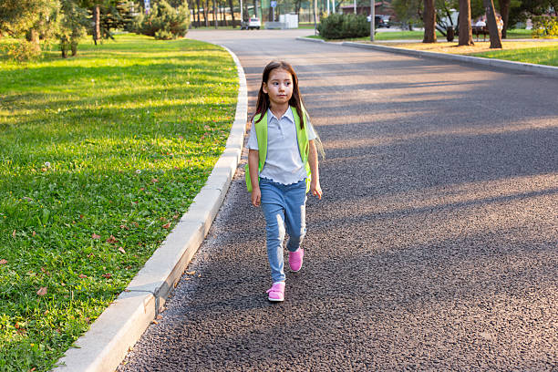 istock Young girl walking on park pathway with backpack in sunny weather 2209798762