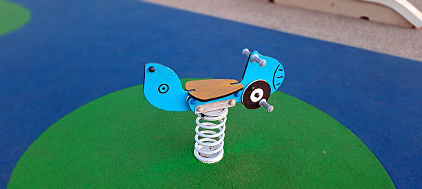 Blue fish-shaped spring rider awaits children on a playground, symbolizing fun and outdoor activity