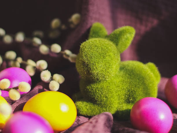 Easter composition with a colorful eggs and figurine of a bunny on brown rustic table