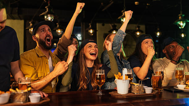 istock Excited friends cheering while watching sports in a pub 2209806663