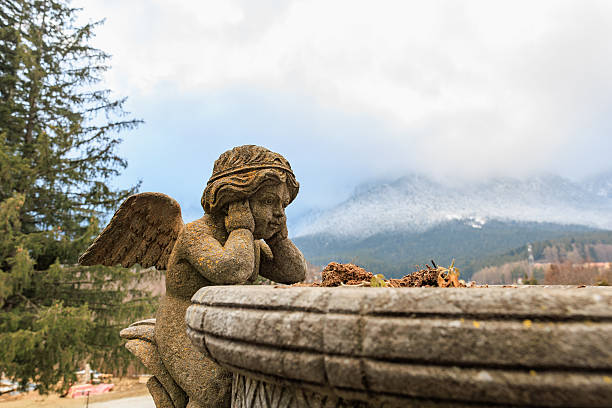 Weathered stone angel sculpture overlooking snowy mountain landscape.