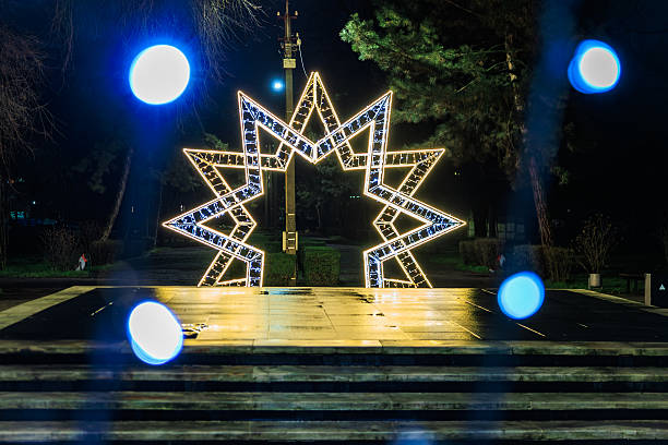 istock Illuminated star sculpture in park at night with festive lights 2209812853