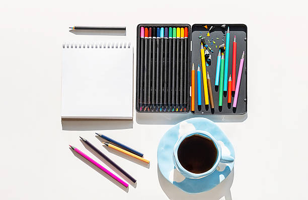 Artistic Workspace Arrangement with Open Colored Pencil Box and Sketchbook in Natural Light. Art Therapy for Relaxation.