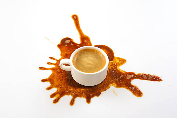 istock A white coffee cup sits on a pristine surface with a rich brown coffee spill spreading outward, creating an artistic pattern. The dark espresso contrasts beautifully with the clean background 2209817703
