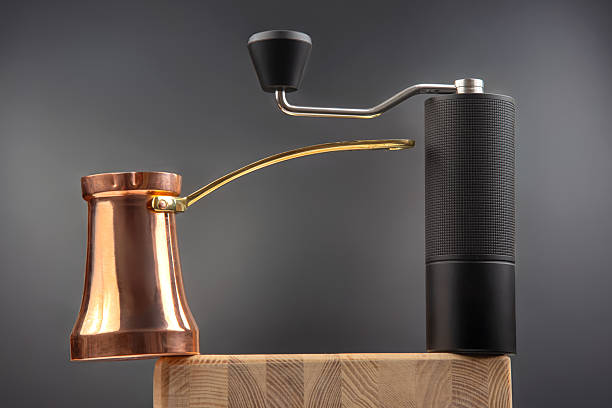 istock a black coffee grinder with a metallic crank beside a copper cezve with a gold handle, great for kitchen stock photos. 2209818232