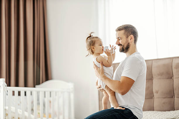 istock A father is holding his daughter in hands while she is looking at him and drinking water from bottle 2209821403