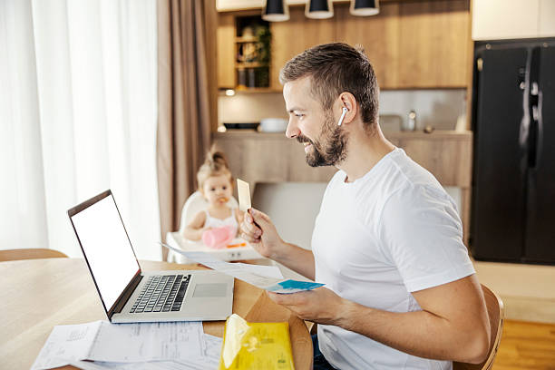 istock A happy father is paying bills online on a laptop while babysitting his daughter. 2209822014