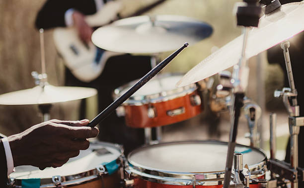Close-up of a traditional drum set up for a performance, surrounded by additional instruments and technology on a vibrant red carpet.