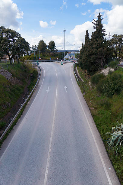 istock Empty two-lane road leading to a roundabout under a cloudy sky 2209835143