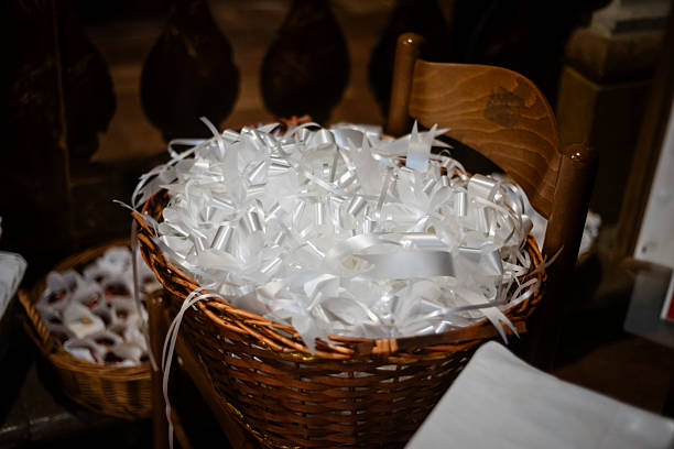 A woven basket filled with curling white ribbons sits in a venue, prepared for a special occasion like a wedding or celebration.