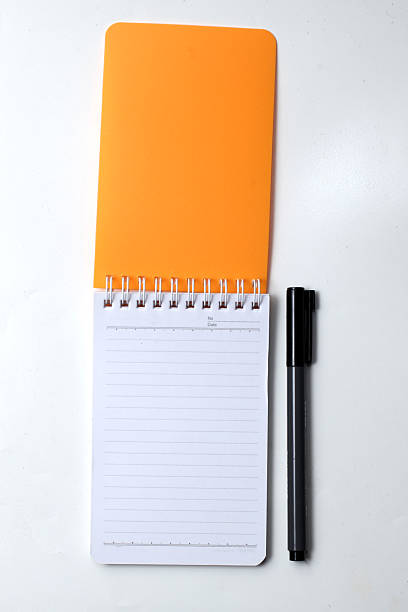 istock small orange notebook and pen isolated on white background, in open position 2209839631