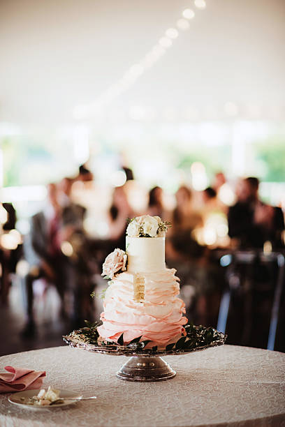 Tiered ombre wedding cake at wedding reception with slice cut by bride and groom