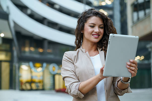 istock Professional Young Woman In Beige Blazer Using Digital Tablet Outside Modern Office Building 2209843068