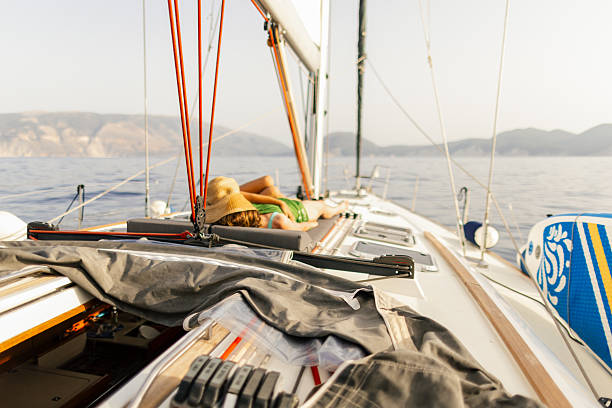Mother and son have fun and sunbathing together on sailboat. They are lying on boat deck and enjoying sailing on Ionian see in Greece