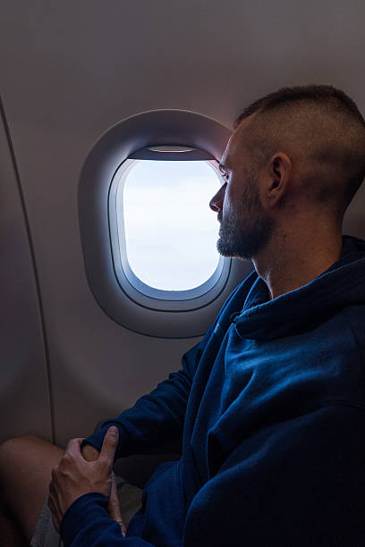 istock Young man looking out from airplane window during flight 2209849052