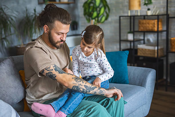 istock Tattooed man showing his daughter tattoos on his hand 2209849607