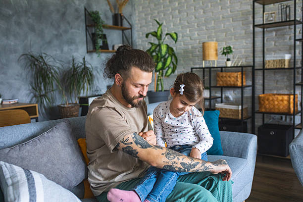 istock Tattooed man showing his daughter tattoos on his hand 2209850002