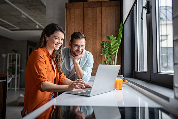 istock Young couple browsing internet on laptop in modern kitchen 2209851686