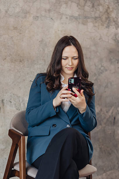 istock Confident businesswoman using smartphone while sitting in modern office space 2209854329