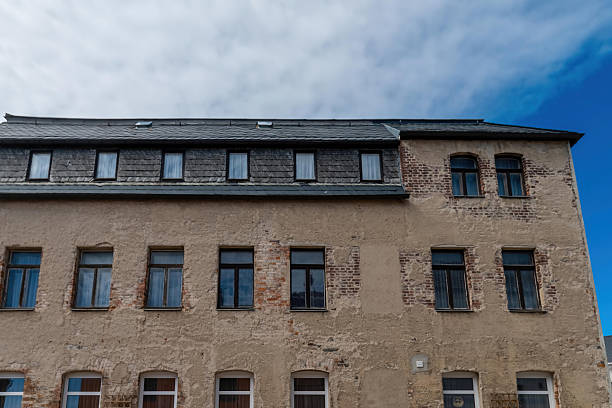 istock Old stone building with multiple windows under a cloudy sky in a quaint town setting 2209855401
