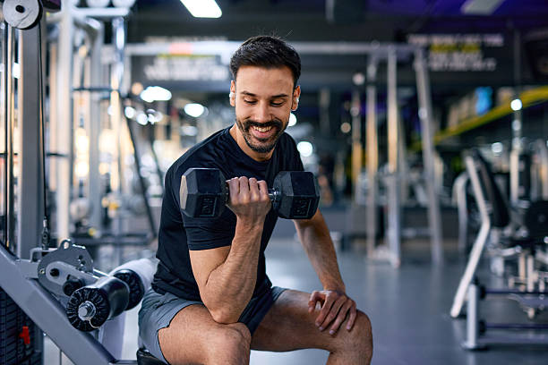 istock Young man lifting dumbbell and smiling during workout at the gym 2209855573