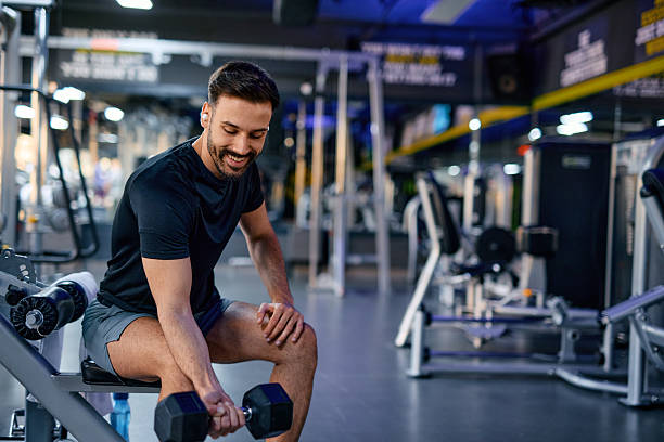 istock Young athletic man lifting dumbbell and exercising biceps in gym 2209855577