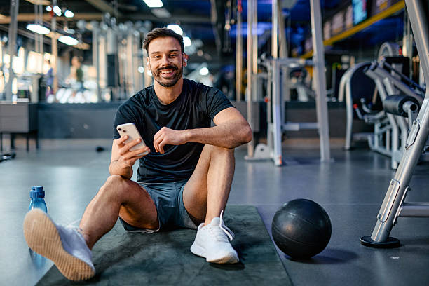 istock Smiling sportsman using smartphone and resting after training in gym 2209855633