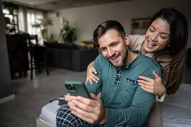istock Happy couple wearing pajamas using smartphone at home 2209861081
