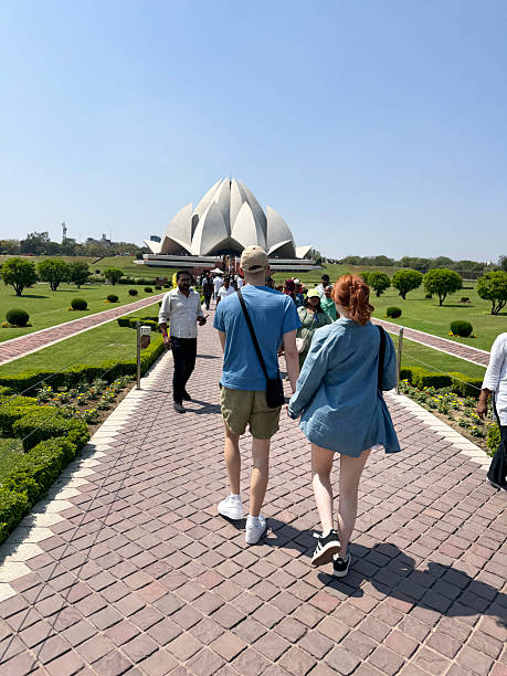 Kalkaji, New Delhi, Delhi, India - March 21, 2025: People walking through formal gardens on a sunny day to visit the Lotus Temple, a Baháʼí House of Worship in New Delhi, India.