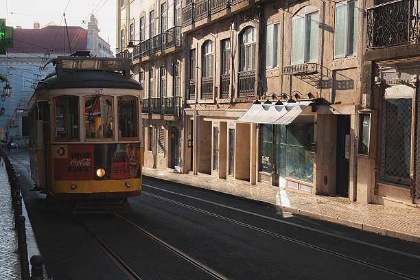 Lisbon, Portugal - July 15,2024: Tram 28 navigates a historic street in Bairro Alto, Lisbon, during the golden hour, capturing the vintage charm and vibrant city life of this Portuguese destination at sunrise.