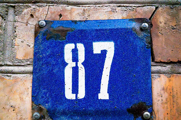 Blue House Number 87 Sign on Brick Wall