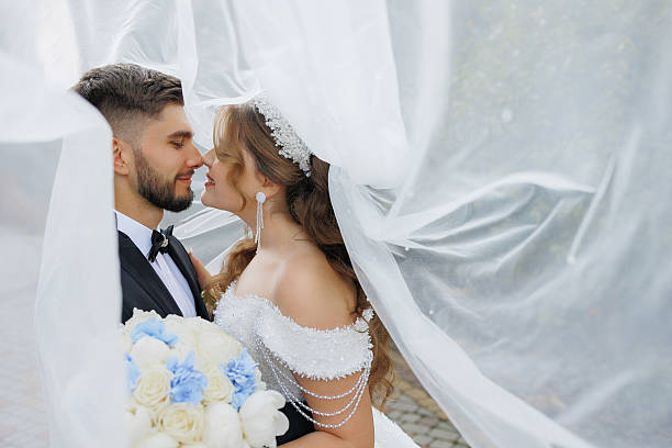 istock A bride and groom are kissing under a white veil 2209885228