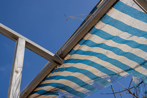 Wooden construction on a roof af an abandoned house. Broken blue and white striped textile shade and a bright blue sky. Galdar, Las Palmas, Gran Canaria, Canary Islands, Spain.